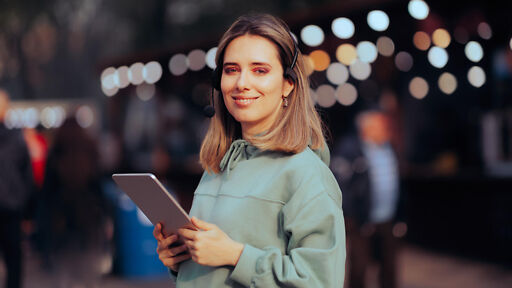 Eventmanagement Studium – Frau mit Tablet und Headset lächelt Eventmanagement Studium – Frau mit Tablet und Headset laechelt