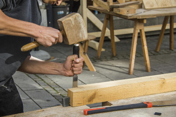 Zimmerer arbeitet mit Hammer und Meißel