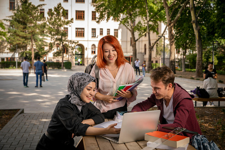 Studierende vor der Uni vertieft in eine Gruppenarbeit im Studium Religionswissenschaft