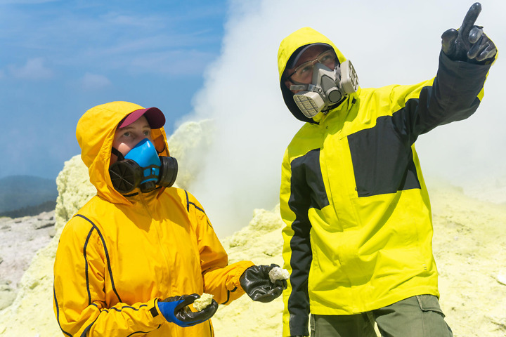 Dozent und Studierende erforschen Gestein auf Exkursion im Vulkanologie Studium